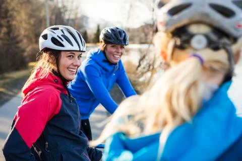 Three young women talking while on their bicycles on a trail at sunrise Stock Photos