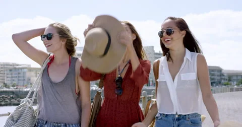 Three young women tourists on summer vacation girl friends walking on beach Stock Footage