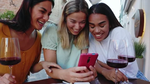 Three young women using mobile phone while enjoying appetizer in a bar Stock Footage 283407609