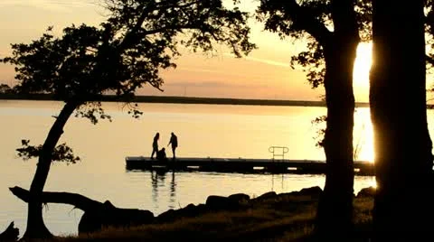 Three young women watching the sunset from the dock at Far West Reservoir near Stock Footage
