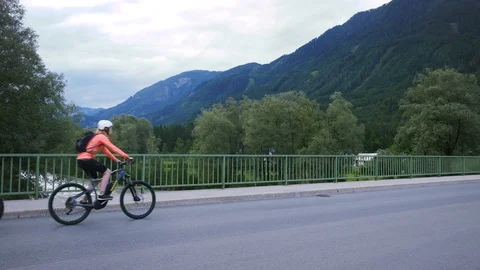 ThreeCyclistsCrossBridge left to right Stock Footage 118402828