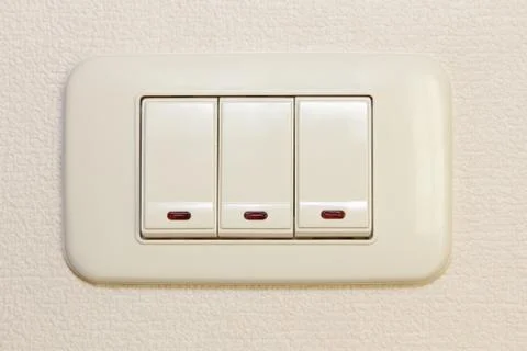 Threefold multiply light switch on beige wall. Stock Photos