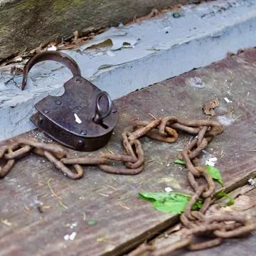 On the threshold lies an old open lock and next to it is a rusty chain Stock Photos