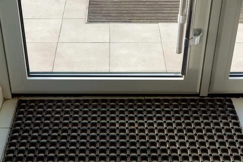 Threshold with a rubber foot mat in the front glass door of the office. Stock Photos