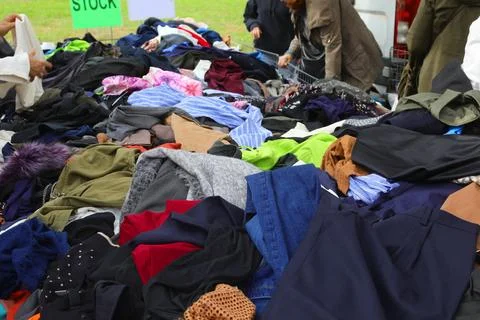 Thrift store booth packed with quality preowned garments piled up at the fl.. Stock Photos
