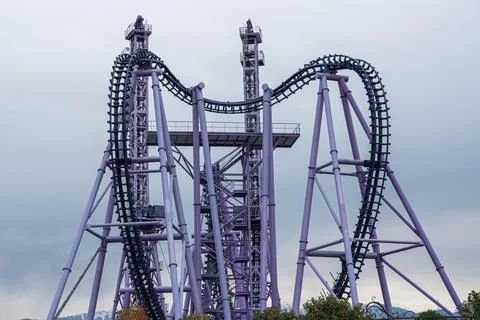 Thrilling roller coaster structure at amusement park under cloudy sky Stock Photos