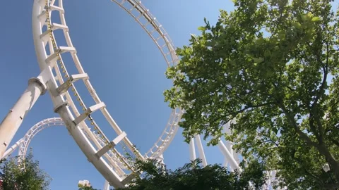 Thrilling roller coaster surrounded by greenery on a sunny day in the amuseme Stock Footage 324874308