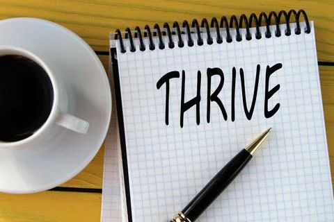 THRIVE - word on a white sheet on a yellow wooden background with a pen and.. Stock Photos