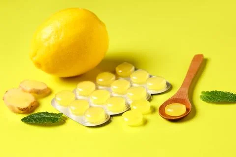Throat lozenges with ginger root, mint leaves and lemon on yellow background, Stock Photos