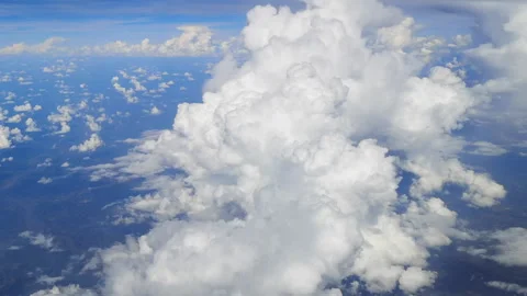 Through the airplane window, clouds roll by like soft mountains of white. Stock Footage 318742073