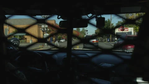 Through Blurred Backseat Cage Patrol Car Drives on Downtown City Street Stockbeeldmateriaal 208752817