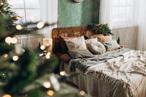 Through Christmas tree view of a large double bed with wooden headboard in a Foto stock