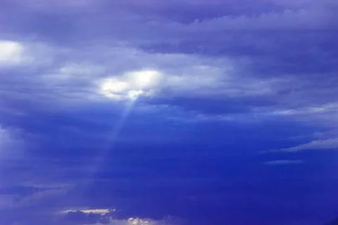 Through the clouds over the sea a ray of sunshine makes its way Stock Photos