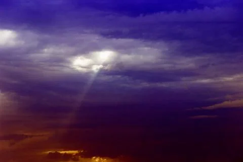 Through the clouds over the sea a ray of sunshine makes its way Stock Photos