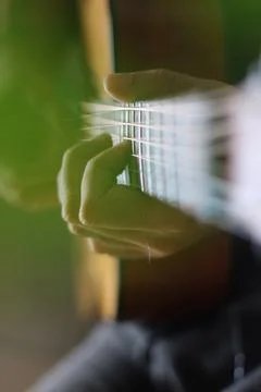 Through the cut-outs of a monstera leaf, hands can be seen playing chords a.. Foto stock