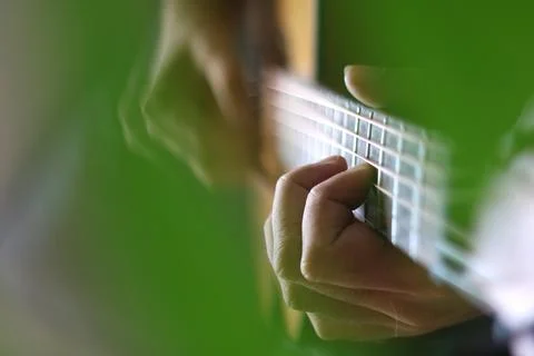 Through the cut-outs of a monstera leaf, hands can be seen playing chords a.. Stock Photos