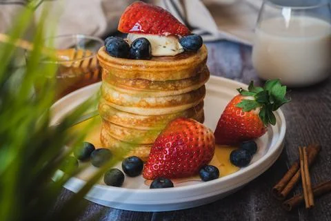 Through the grass view of Stack of pancakes with honey stick, strawberry, blu Stock Photos