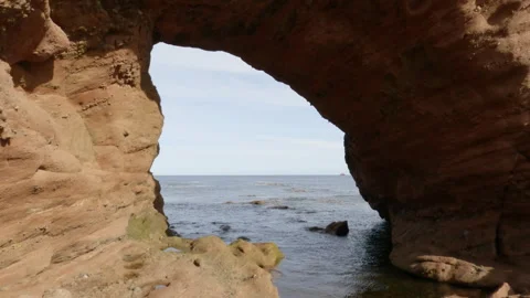 Through a natural arch in Aberdour beach area in Scotland. Stock Footage 322076069