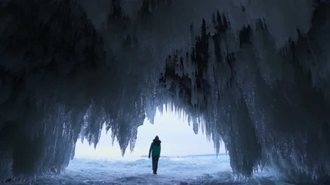 Through transparent sharp icicles winter cave lake Baikal, tourist walk inside Stock Footage 165663760