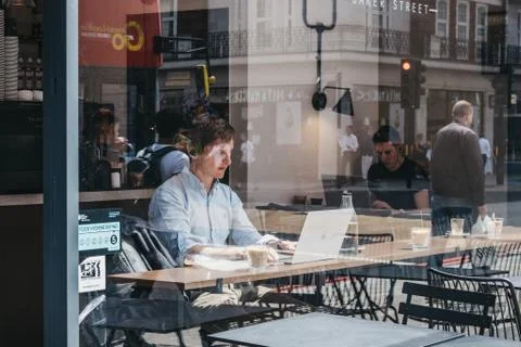 Through the window of men working on laptops inside a cafe in Marylebone, Lon Stock Photos
