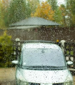 Through the window splashed with autumn rain one can see a car standing in th Stock Photos