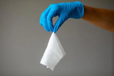 Throw a damp wet wipe into the trash, hand in blue protective glove Stock Photos