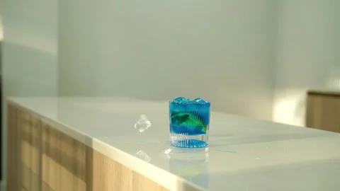 Throw ice cubes in blue cocktail in the glass. Ice Cubes are falling down. Make Stock Footage 307273559