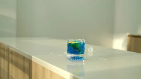 Throw ice cubes in blue cocktail in the glass. Ice Cubes are falling down. Make Stock Footage 307274453