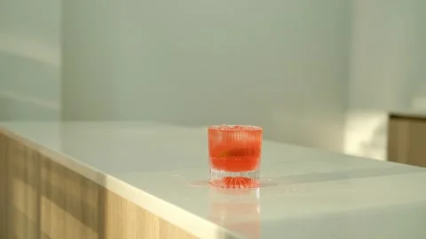 Throw ice cubes in orange or red cocktail in the glass. Ice Cubes are falling Stock Footage 307273943
