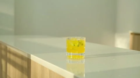 Throw ice cubes in yellow cocktail in the glass. Ice Cubes are falling down Stock Footage 307274845