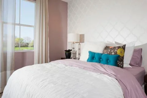 Throw pillows arranged on bed in average house Stock Photos