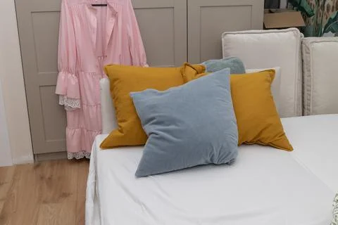 Throw pillows on white sofa with pink robe hanging indoor Stock Photos