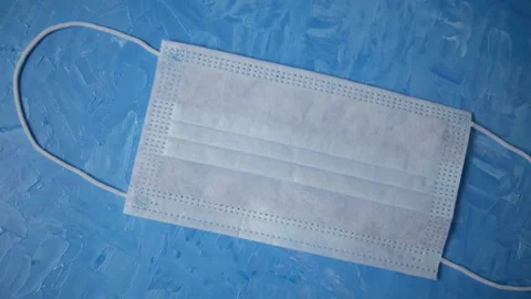 Throw the protective medical mask on the table. Background of blue artistic oil  Stock Footage 149831538