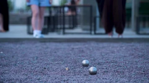 Throwing and knocking metal balls in a game of petanque on a gravel court Stock Footage 310662793