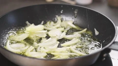 Throwing and stirring of sliced onion into frying pan. Stock Footage 152529964