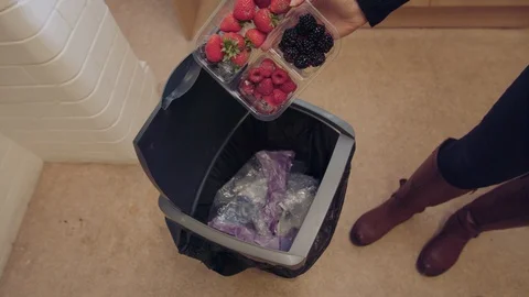 Throwing away a packet of fruit and plastic packaging into a bin Stock Footage 95187531