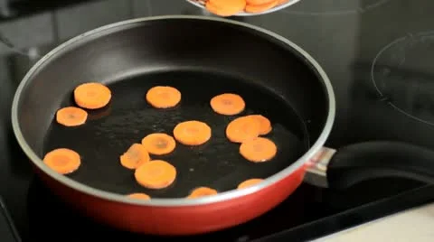 Throwing carrots into a frying pan Stock Footage 12758616