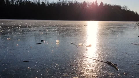 Throwing a chunk of ice that crushes on a frozen lake. Sunny winter day. Slow Stock Footage 146693799