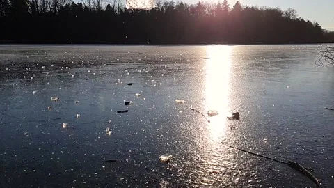 Throwing a chunk of ice that crushes on a frozen lake. Sunny winter day. Slow Stock Footage 146694101