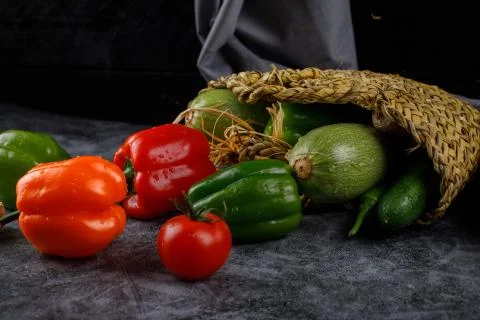 Throwing colorful bell peppers from a rustic basket. Stock Photos