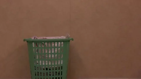 Throwing dirty laundry into green laundry basket - wide Stock Footage 149727805