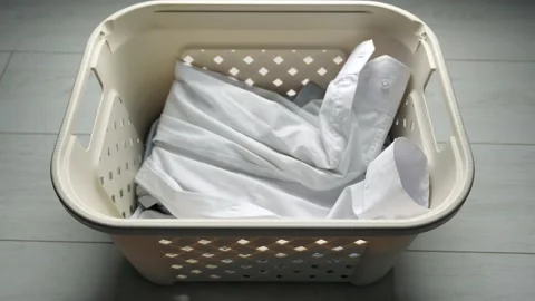 Throwing dirty laundry inside laundry basket near washing machine Stock Footage 130699195
