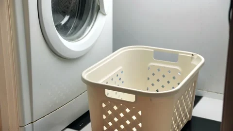 Throwing dirty laundry inside laundry basket near washing machine Video stock 134940346