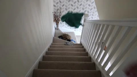 Throwing dirty laundry from top to bottom of stairs in modern home Video stock 136314267