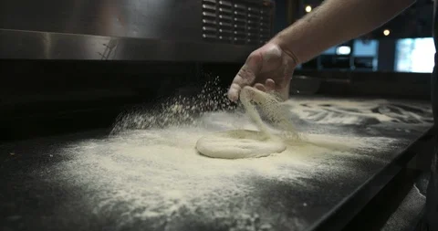 Throwing down flour and getting prepared to toss and roll dough by hand Stock Footage 104967382