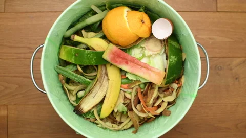 Throwing fruit and vegetable peels to a bin full of organic waste Stock Footage 134612731