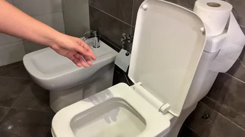 Throwing garbage into the toilet, hand holds rotten banana peel over clean wc Stock Footage 311809949