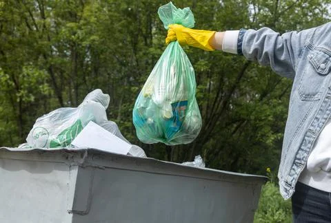 Throwing garbage into a trash can. Close-up of a hand holding a garbage bag over 스톡 사진