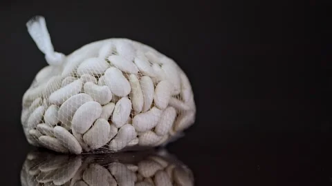 Throwing a nylon mesh bag containing white beans onto a mirror-like black s.. Stock Footage 263027536
