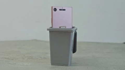 Throwing obsolete mobile phones into small rubbish can for electronic waste Video stock 340574337
